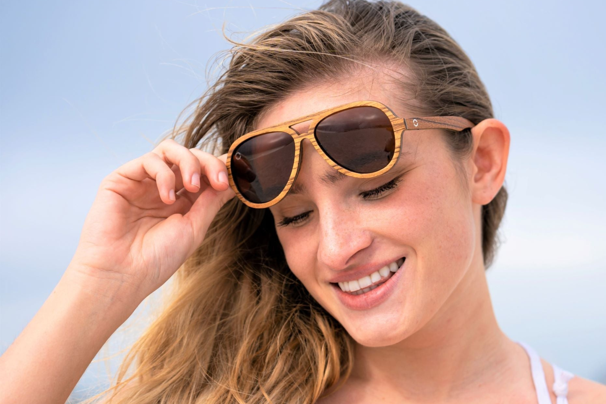 A girl wearing wooden sunglasses at beach in florida